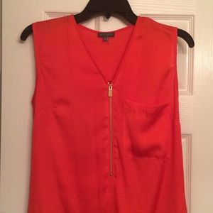 Deep orange sleeveless top with gold zip